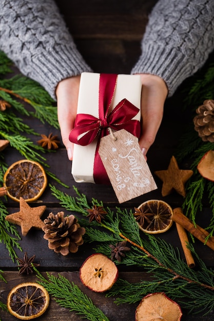 Vrouw met kerstcadeautjes gelegd op een houten tafel.