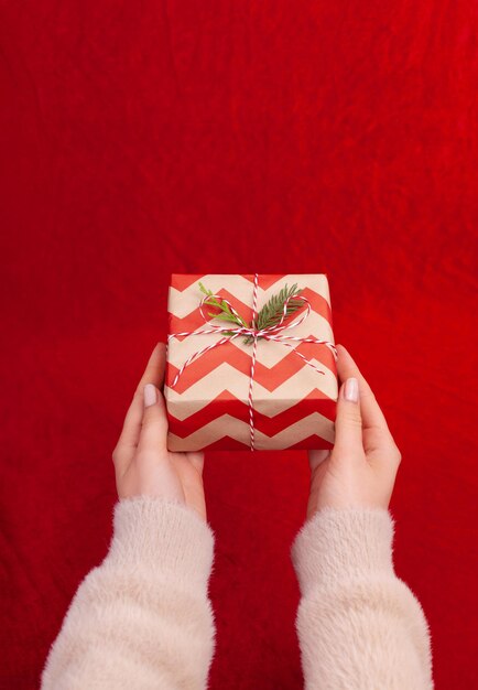 Vrouw met kerstcadeautjes op een rode tafelachtergrond..