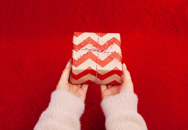 Vrouw met kerstcadeautjes op een rode tafelachtergrond..