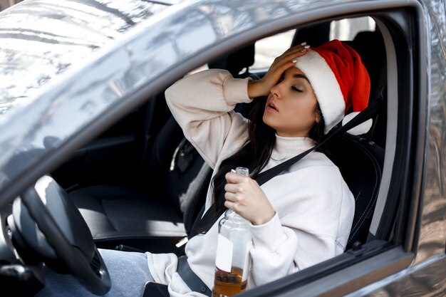 Vrouw met kerstmuts drinken achter het stuur