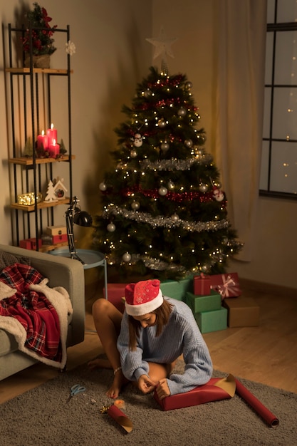 Vrouw met kerstmuts inwikkeling van cadeaus voor kerst