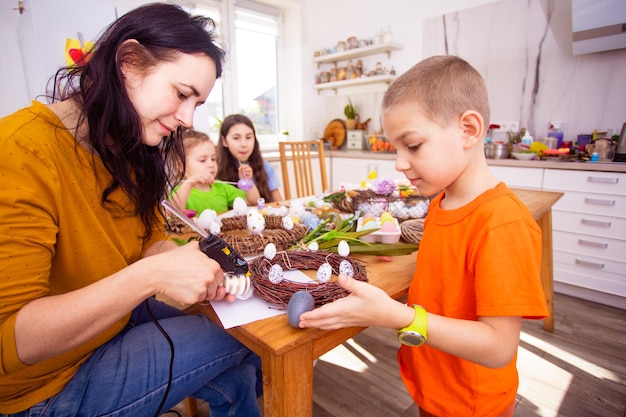 Vrouw met kinderen die versieringen maken voor Pasen