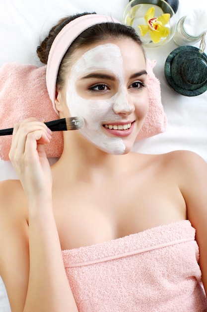 Vrouw met klei gezichtsmasker in beauty spa