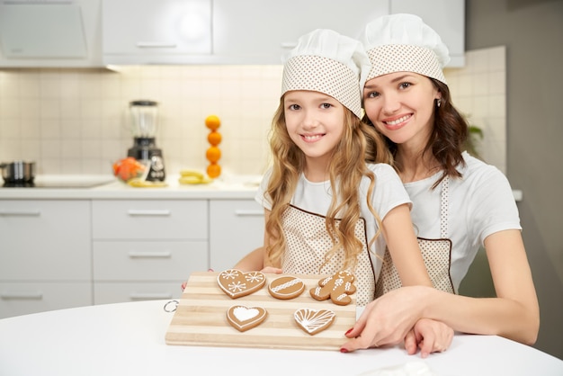 Vrouw met kleine dochter die dienblad met koekjes houdt