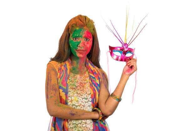 vrouw met kleurrijk gezicht carnaval masker houden en vieren holi.