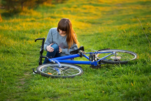Vrouw met kniepijn na het fietsen in het park bij zonsondergang