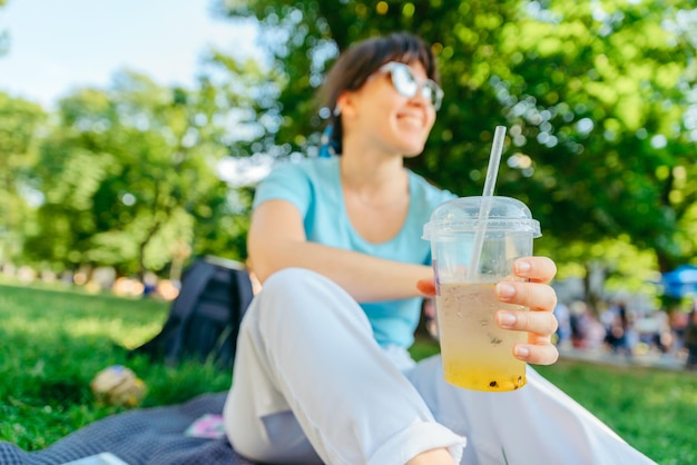 Vrouw met koel drankje in stadspark wazig achtergrond brede engel