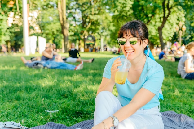 Vrouw met koel drankje in stadspark wazig achtergrond