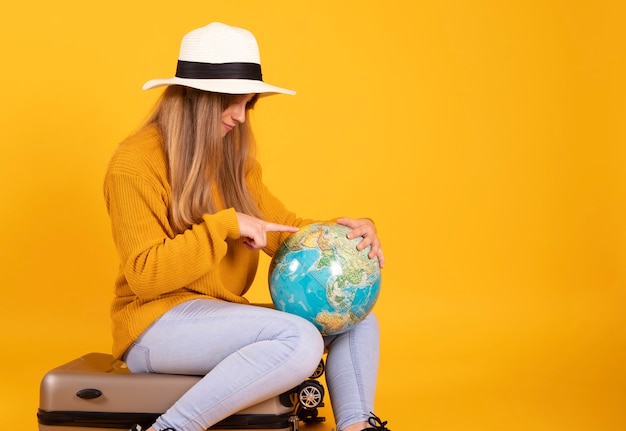 Vrouw met koffer en hoed kijkt naar earth globe wil reizen