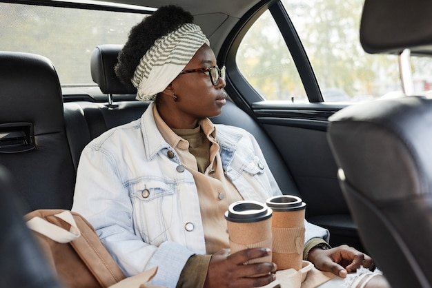 Vrouw met koffie zittend in taxi