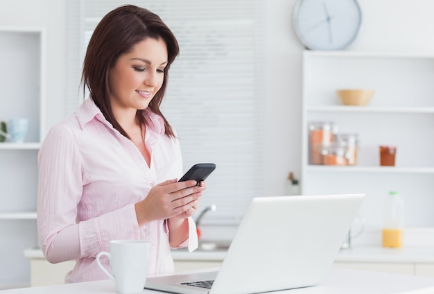 Vrouw met koffiekop en laptop die cellphone gebruiken