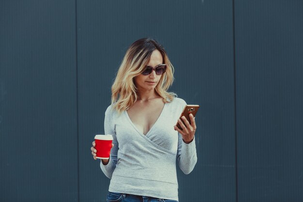 Vrouw met koffiekopje en smartphone. mode zakendame