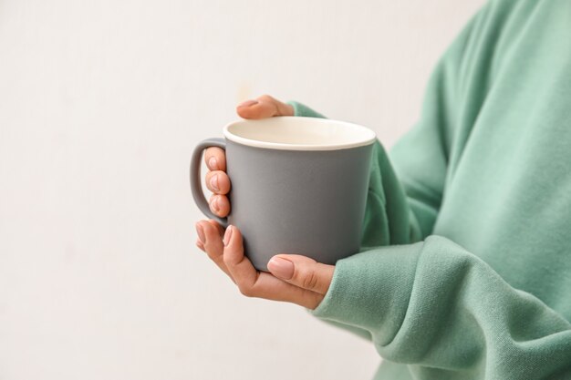 Vrouw met kop hete thee op lichte ondergrond