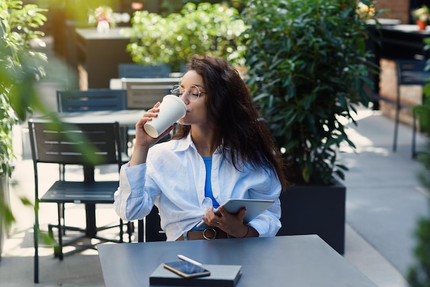 Vrouw met kopje koffie werken op terras in de ochtend