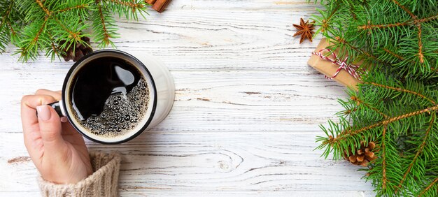 Vrouw met kopje warme koffie op rustieke houten tafel. handen in warme trui met mok, winterochtend of kerst concept