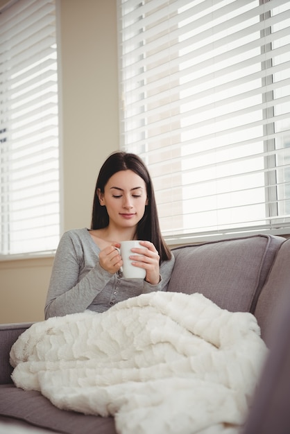 Vrouw met kopje zittend op de Bank