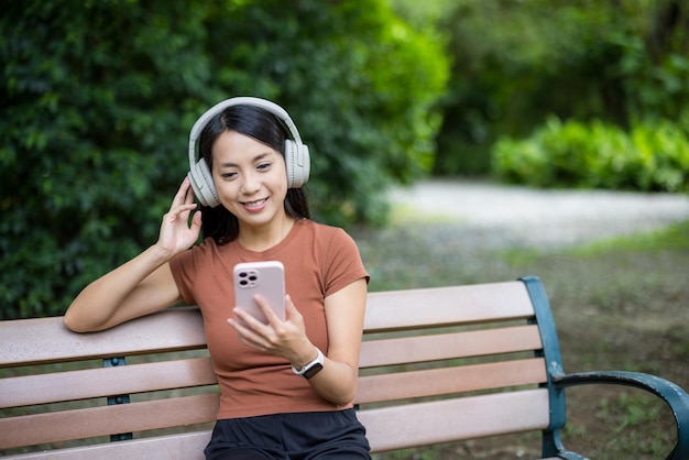 Vrouw met koptelefoon en kijk naar de mobiele telefoon in het park