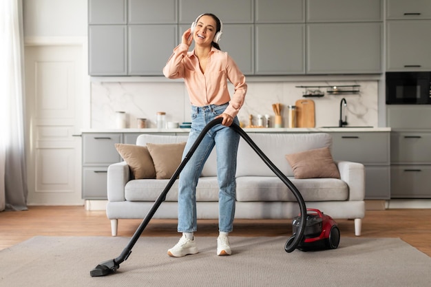 Vrouw met koptelefoon geniet van het stofzuigen van haar huis