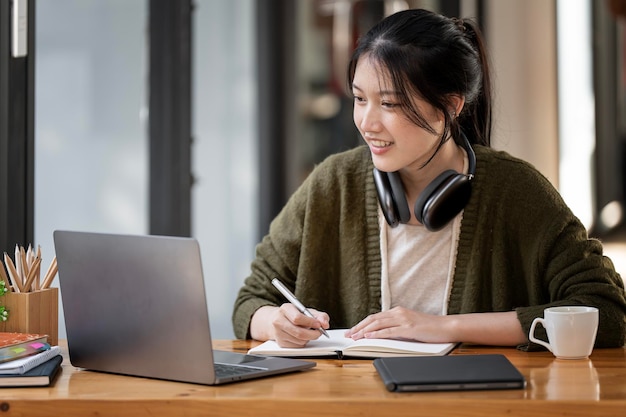 Vrouw met koptelefoon met behulp van laptop in café schrijven notities aantrekkelijke vrouwelijke student leren online luisteren audio cursus e-learning onderwijs concept