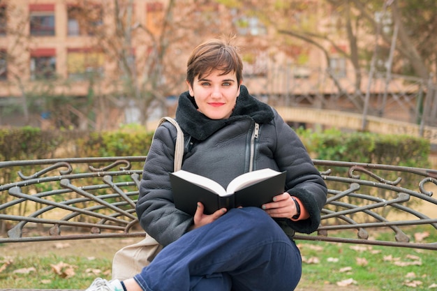 Vrouw met kort haar camera kijken en lachend met een boek in haar handen