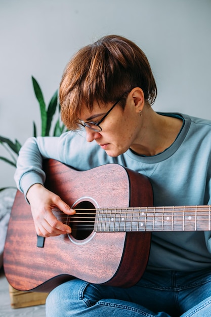 vrouw met kort haar speelt graag gitaar thuis muzieklessen voor volwassenen