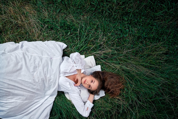 Vrouw met kussen en deken liggend op groen veld