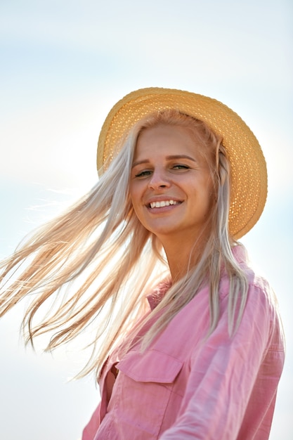 Vrouw met lang blond haar en een strooien hoed in een tarweveld