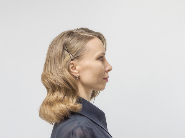 Vrouw met lang blond haar en elegant kapsel in retro stijl van golvend haar in een schoonheidssalon. Zijaanzicht.