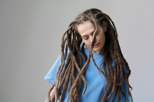 Foto vrouw met lange dreadlocks die op wit staat met gesloten ogen