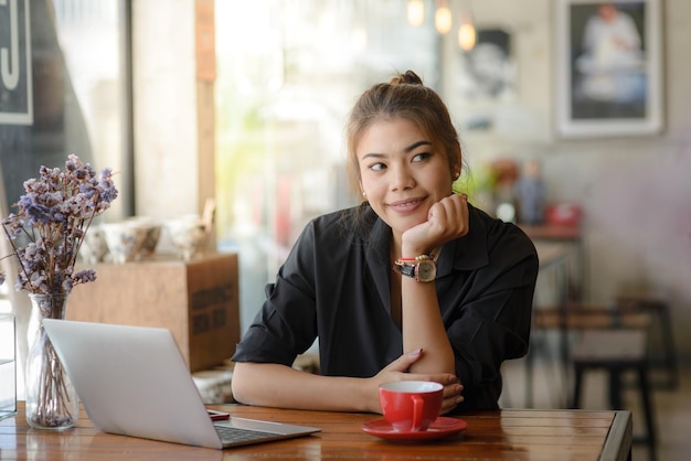 Vrouw met laptop die aan tafel zit in een restaurant