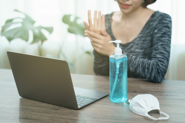 Vrouw met laptop die desinfecterend middel gebruikt