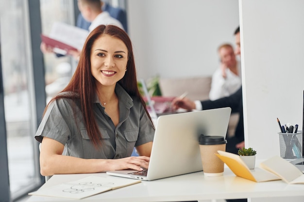 Vrouw met laptop Groep mensen in officiële formele kleding die binnenshuis op kantoor is