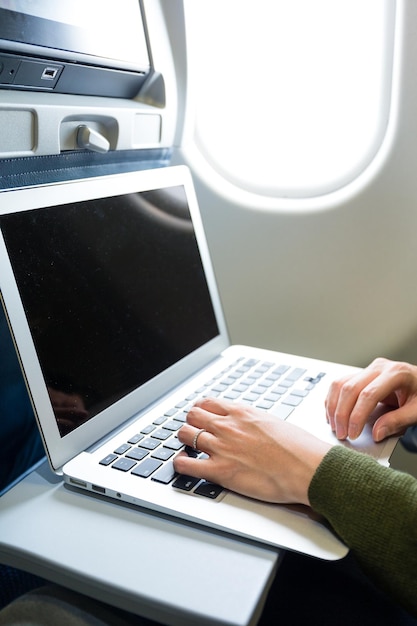 Vrouw met laptop in het vliegtuig