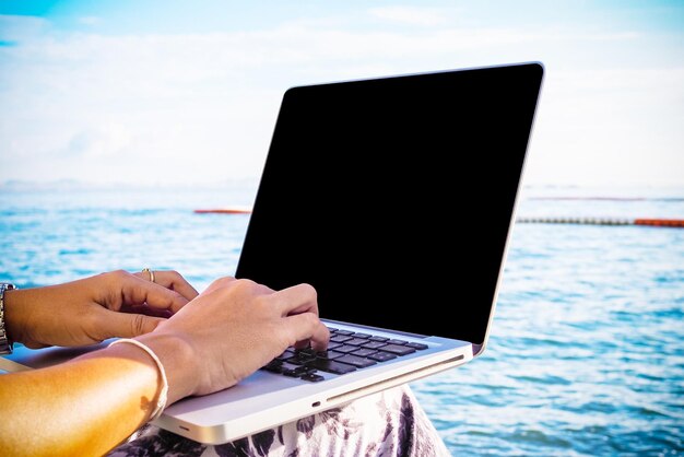 Foto vrouw met laptop op het strand