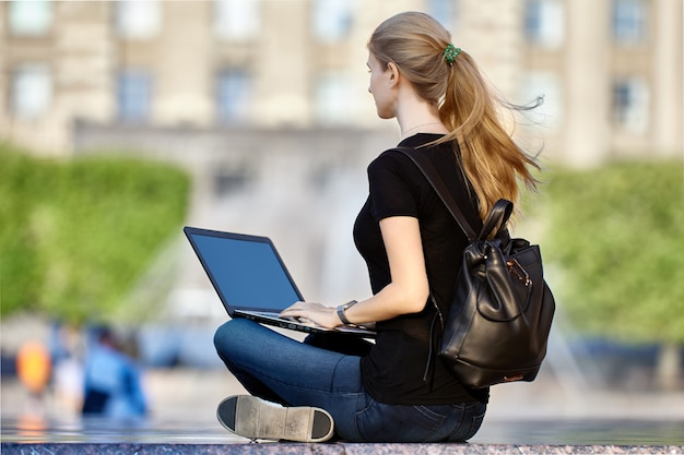 Vrouw met laptop zit in de stadstuin op zomerdag