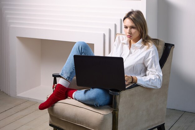 Vrouw met laptop zit in fauteuil in lounge interieur