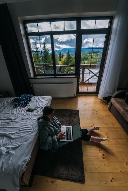 Vrouw met laptop zittend op de vloer en werkend op laptop