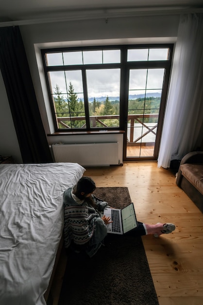 Vrouw met laptop zittend op de vloer en werkend op laptop