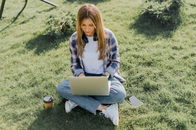 Vrouw met laptop zittend op het gras