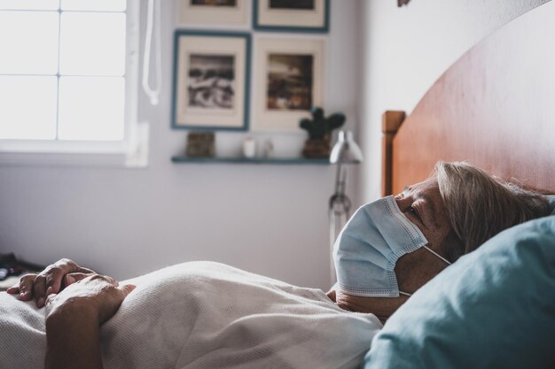 Vrouw met masker terwijl ze thuis op bed ligt