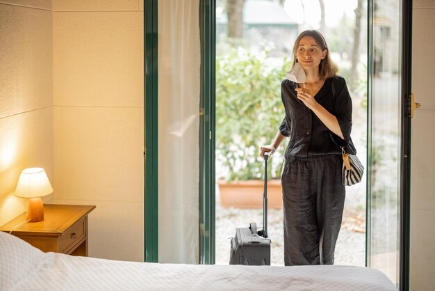 Vrouw met medisch masker komt hotelkamer binnen