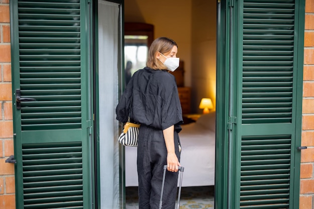 Vrouw met medisch masker met bagage komt hotel binnen