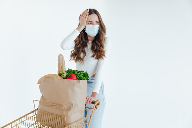 Vrouw met medisch masker met een boodschappentas vol vers voedsel.