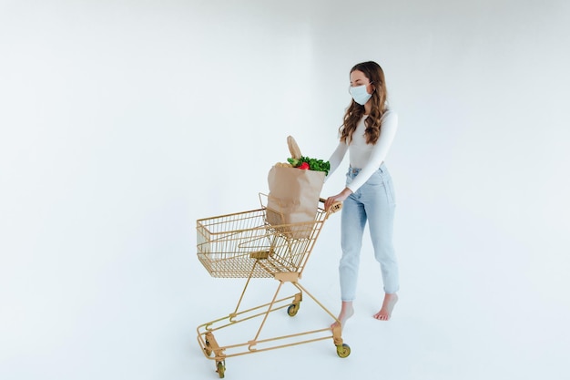 Vrouw met medisch masker met een boodschappentas vol vers voedsel.