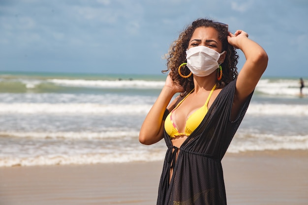 Vrouw met medisch masker op het strand, nieuwe normale regels, webbanner. Leven na pandemie, verplicht gebruik van gezichtsmasker in openbare ruimtes, kopieer ruimte