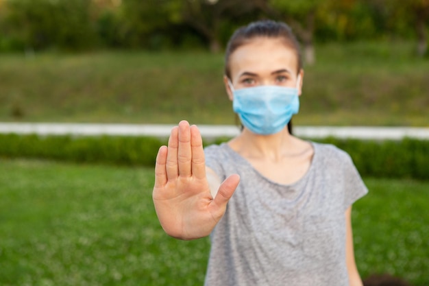 Vrouw met medisch masker toont stopgebaar met de hand