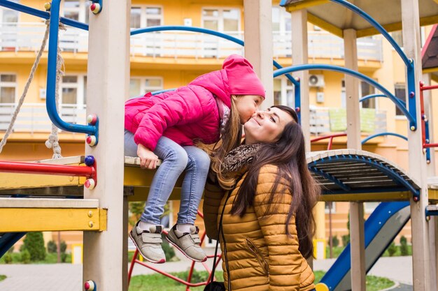 Foto vrouw met meisje op speelplaats dochter kust haar moeder