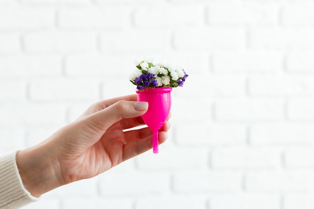 Vrouw met menstruatiecup met bloemen close-up