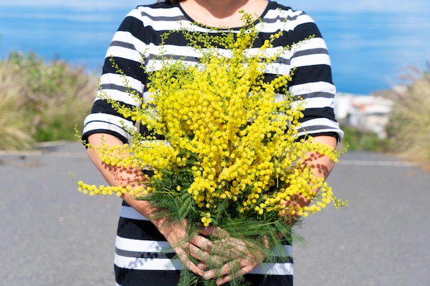 Vrouw met mimosa bloemen boeket 8 maart dag feestelijke achtergrond mimose is traditionele bloemen voor internationale vrouwendag 8 maart