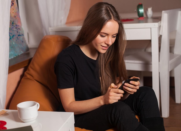 Vrouw met mobiele telefoon en kopje koffie